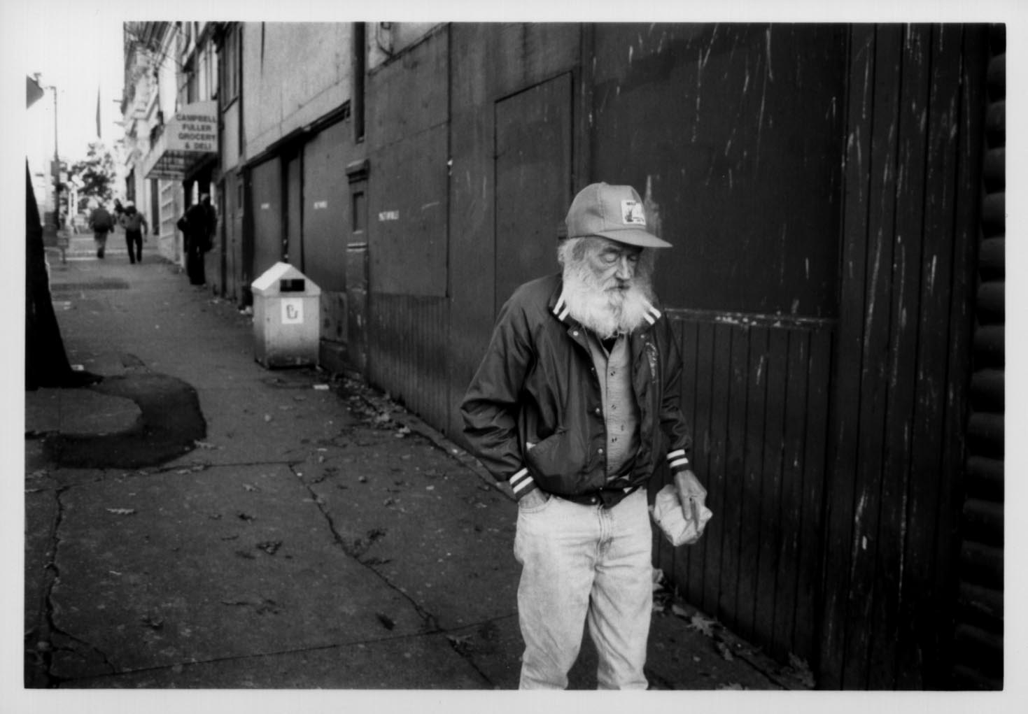 Elderly homeless man walking on sidewalk