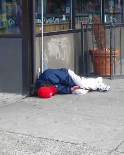 Photo of homeless man lying on sidewalk
