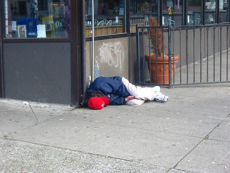Photo of homeless man lying on sidewalk
